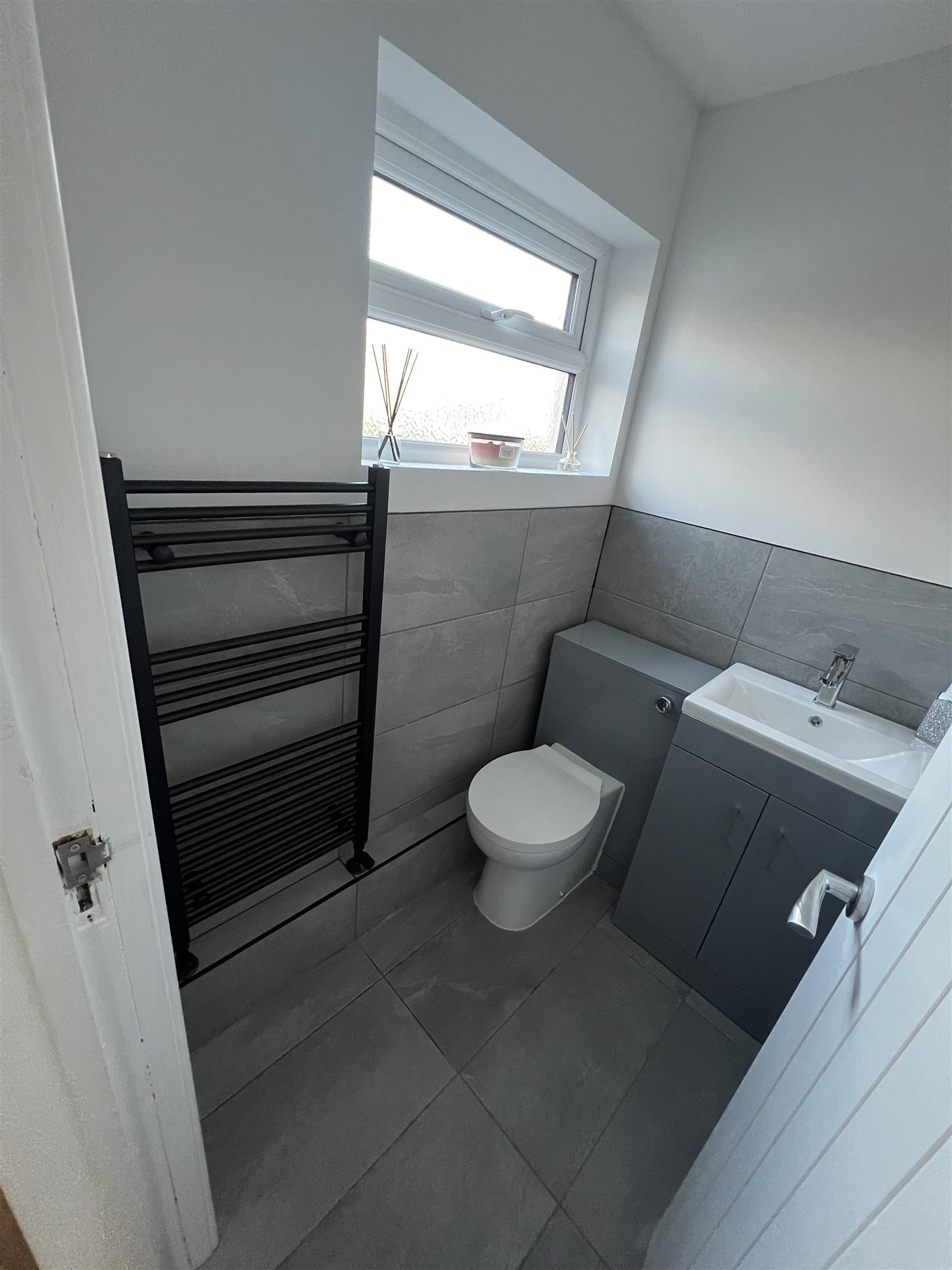 Modern grey tile bathroom with black towel radiator, full renovation