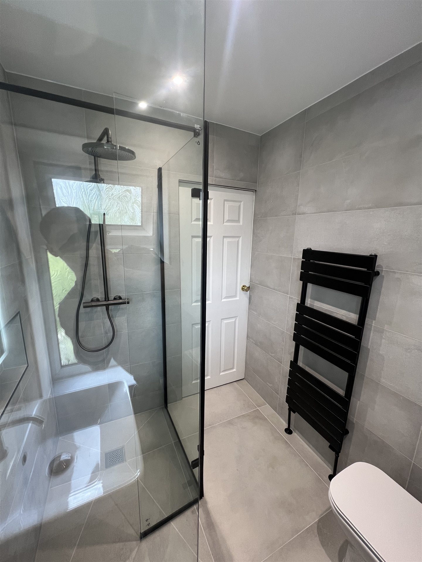 Grey stone-effect bathroom with matte black fittings and walk-in shower