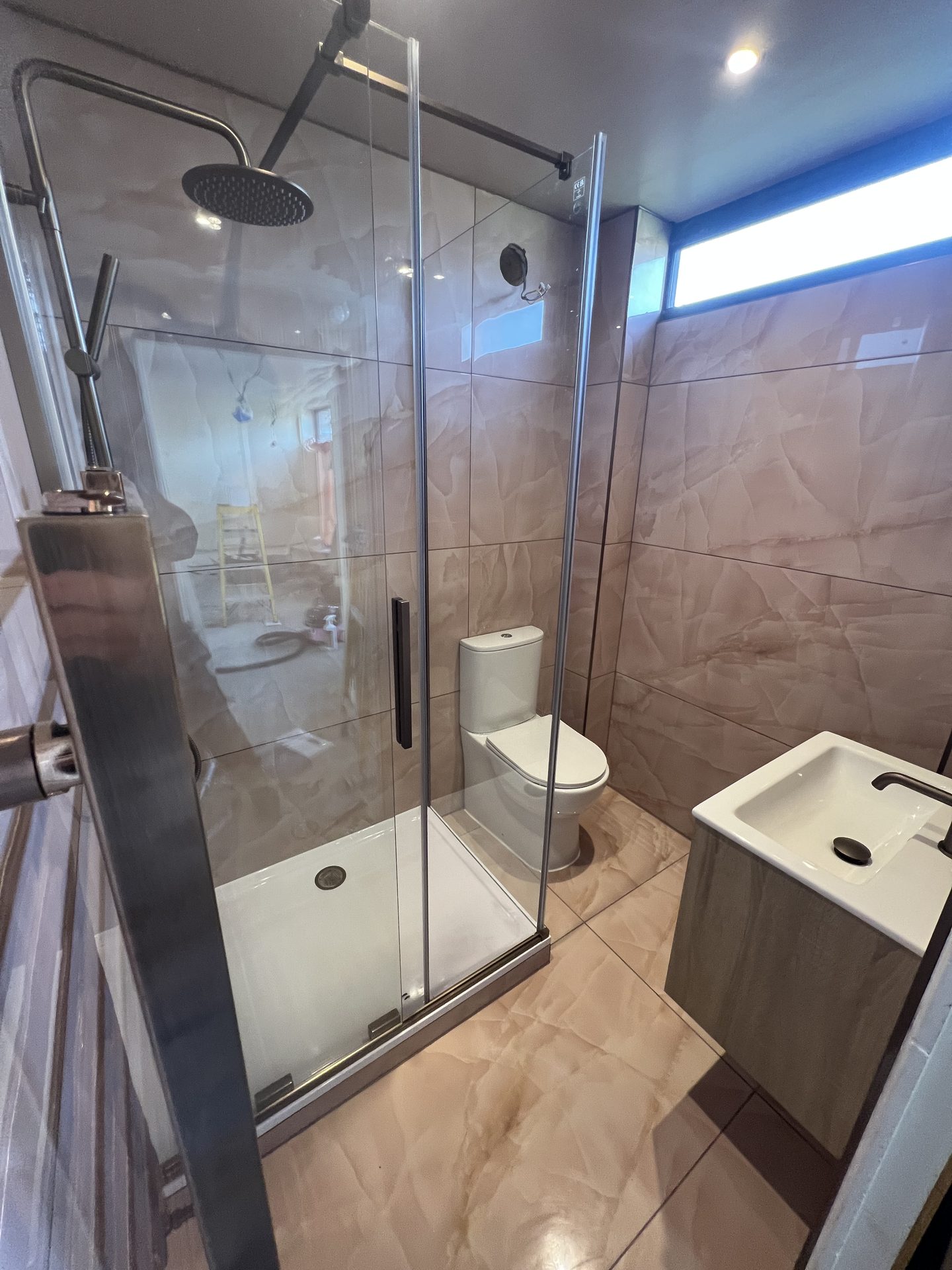 Tan stone-effect bathroom with frameless glass shower enclosure